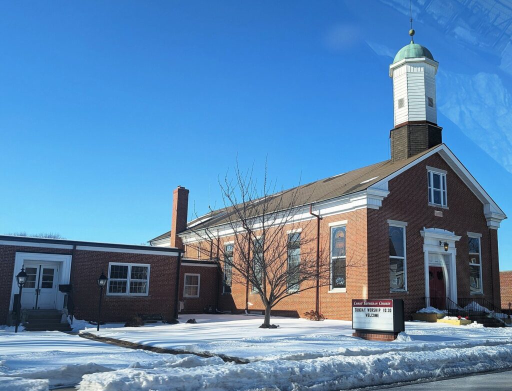 Brick Christ Lutheran Church with a white cupola in Manchester, Pennsylvania, on a snowy day
