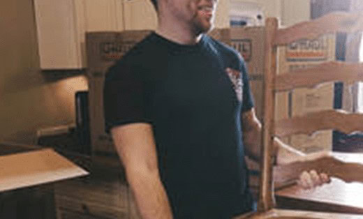 A & M Friendly Movers mover carrying a chair past packed boxes